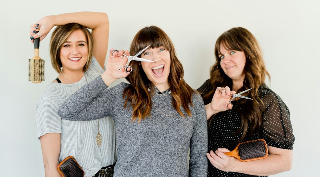 three women holding scissors and brush